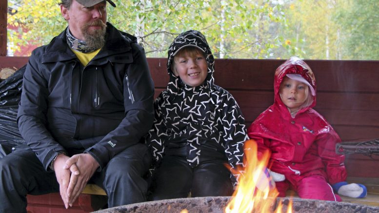 Vesa, Atso ja Enna Ylipahkala nautiskelivat nuotion lämmöstä ja katoksen tarjoamasta sateensuojasta Leuvan syysriehassa viime lauantaina. Oulussa asuva perhe oli tullut kyläilemään Leuvan mummulaan ja samalla viettämään mukavaa syyspäivää kylätalolla järjestettyyn tapahtumaan. Seitsemänvuotias Atso muisteli, että aiemmin hän on käynyt samassa paikassa silloin, kun siellä on järjestetty hiihtokilapailut. Molemmat lapset nauttivat Liikkuvan Laulurepun esityksestä ja tutut kappaleet saivat hymyn huulille.