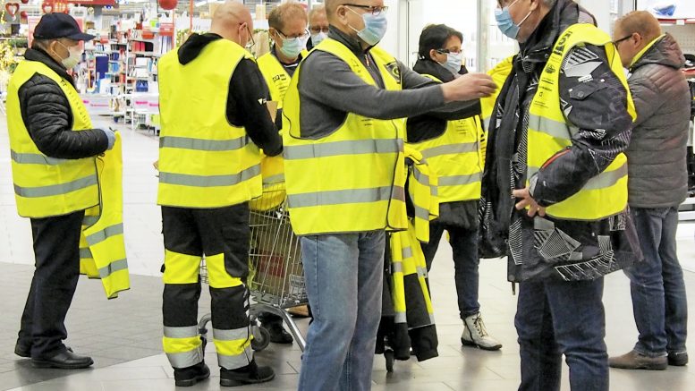 Heijastinliivien jako aloitettiin Iin Kärkkäiseltä, mistä sitä jatkettiin Haukiputaalle K-Supermarketin aulaan. Liivien saajat olivat tyytyväisiä, ja liivejä jakaneet klubilaiset nauttivat yhdessä tekemisestä, vaikka se maskien suojassa ja käsidesin turvin jouduttiinkin suorittamaan. Ismo Piri sovittaa heijastinliiviä saajan ylle, takana vasemmalla Markku Annala, selin Liikenneturvan Kimmo Kokkonen, Aarno Rantapelkonen, Pentti Aula ja Ritva Liedes.