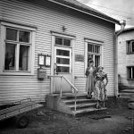 Kaksi naista Haukiputaan Asemakylässä Postisäästöpankin portailla 1950-1955. Kuva Museoviraston Kansantieteen Pekka Kyytisen kokoelmasta.