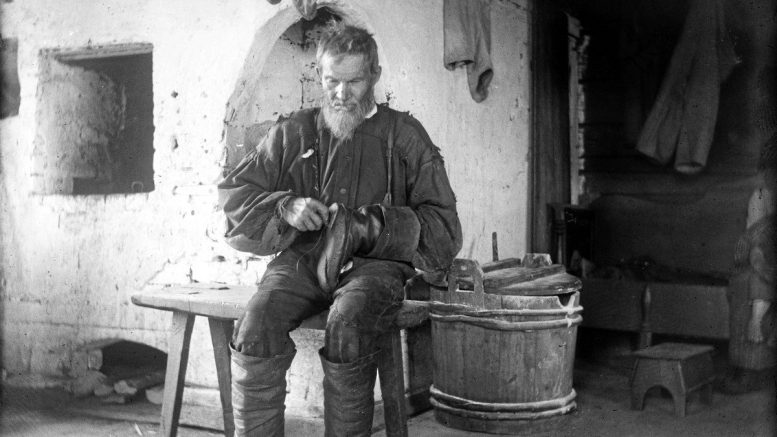 Matti Tyvelä korjaa kenkää. Kuvaaja Samuli Paulaharju, 1913. Museovirasto.