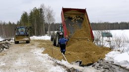 Pehmeän hiekan päällä kuorman purku vaatii varovaisuutta. Timo Niemelä varmistaa, kun Unto Kanniainen peruuttaa traktoria.
