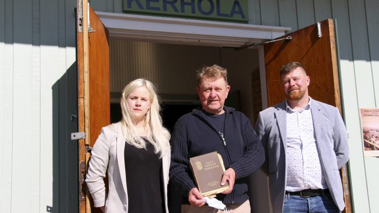 Kerholassa lapsena asunut Sakari Kuparinen (keskellä) toi paikan uusille omistajille Hanna ja Pekka Qvistille tuliaisena harvinaisen kirjan "Pojat kansan urhokkaan", joka kuului aikoinaan Kerholan kirjaston kokoelmiin.
