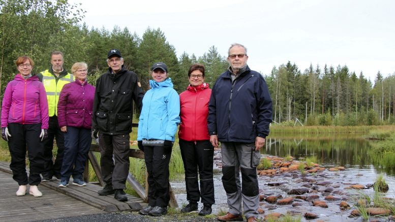 Johanna Liinamaa, Kari Korhonen, Kaarina Väänänen, Birger Ylisaukko-oja, Sanna Alalauri, Mari Perätalo ja Markku Vuolteenaho odottavat muun talkooväen ohella innostuneena Kiimingin – Jäälin Vesienhoitoyhdistyksen tulevia juhlia sekä Koiteli-reitin vihkiäisiä. Taustalla näkyy Kalamäen kosteikkoa jonka maisemissa lauantainen juhla järjestetään.