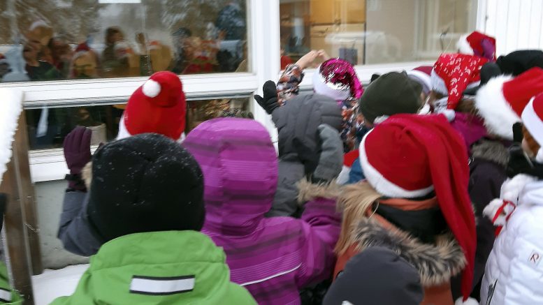 Yli-Iin koulun 1. luokan oppilaat kävivät luovuttamassa tekemänsä joulukalenterin Jokirannan palvelukeskuksen väelle. Tunnelma oli iloinen ikkunan molemmin puolin. (Kuva: Hanna-Leena Tihinen)