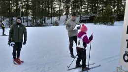 Jarmo Savilaakso lähettää Hilta Turtisen puolen kilometrin kisataipaleelle. Tanja-äiti kannustaa hiihtäjää.