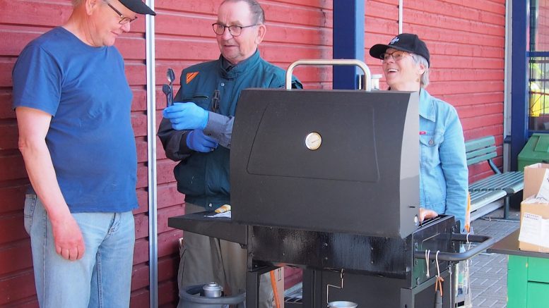 Vuoronvaihto grillin äärellä Kyösti ja Kaisa Hökältä Ismo Pirille. Kyläkauppapäivän makkaratarjoilun hoitivat Yli-Iin reserviläiset.