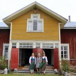 Katri Rundgren, Aino Hakkarainen ja Maarit Hakkarainen ovat kiertäneet vieraiden kanssa isossa rakennuksessa. Katrilla ja Maaritilla on päällä Peräpohjolan kansallispuku, joka täyttää tänä vuonna talon tavoin 100 vuotta.