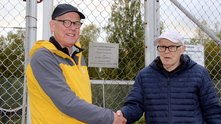 Juhani Suopanki ja Kauko Räisänen saivat vuonna 1989 idean, joka poiki tenniskentän Kiimingin Niemeläntörmälle. Nyt miesten kunniaksi kiinnitettiin laatta kentän oveen. (Kuva: Teea Tunturi)
