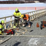 Satamalaiturin rakenteita ja louheverhousta työstämässä Markku Paakkola ja Kyösti Siekkinen Infra Vipuset Oy:stä ja Joonas Outila Kuljetuskartio Oy:stä. Kaivinkonetta on ajamassa Timo Myllykoski Maarakennus Myllykoskesta. Satamalaiturin viereinen jääalue satama-altaassa on aidattu ja merkattu, sillä vettä pidetään sulana.