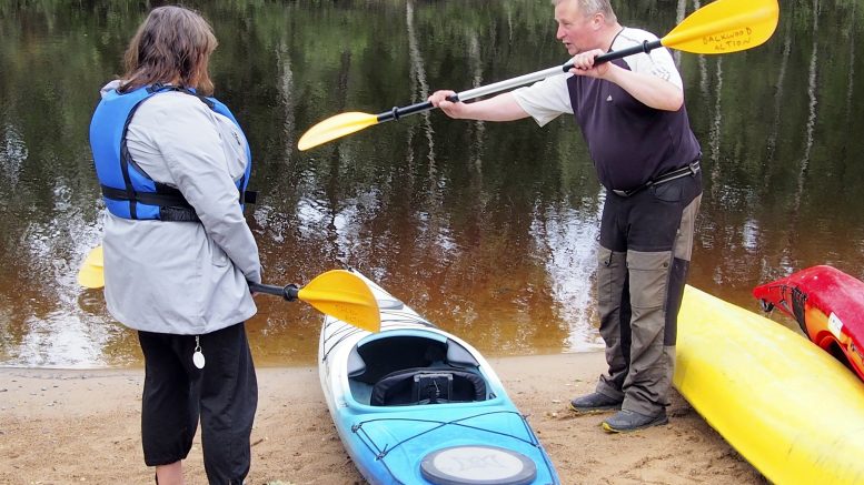 Harri Tapio näyttää oikean melontaotteen, Mervi Koiste seuraa. Heidän väliinsä jäävä kajakki on normaalia tilavampaa mallia, joten se sopii hyvin aloittelevalle melojalle.