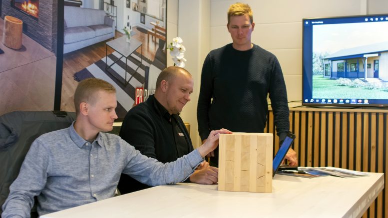 Sauli Taskila, Tapani Pakanen ja Samuli Pakanen esittelevät pöydällä näkyvää CLT-elementin palaa.