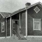 ”Lavosen perhe asui Olhavassa 1930-luvulla ja tuon ajan elämästä Maija Lavonen nosti usein esille omavaraisuuden ja luonnon. Lihaa, perunoita tai maitoa ei ostettu kaupasta, vaan porsas tai lammas kasvatettiin itse tai se ostettiin naapurilta. Kala pyydettiin joesta tai merestä. Ja pimeitä iltoja eivät valaisseet katuvalot vaan tähdet ja kuu. Maija Lavosen rakkaisiin muistoihin kuului myös valokuva, jossa oli joukko kylän naisia ja rukki. Siihen oli ikuistettu kehruukurssi. Kehrääminen oli tärkeä taito, sillä villapaidat sukat, pipot ja vanttuut kudottiin itse kotona kehrätystä villalangasta. Hän muisteli myös omiin leikkeihin saamiaan villalankoja. Voi kuulostaa oudolta, mutta jokainen käsitöitä tekevä ymmärtää villan pehmeyden ja lämmön, ja käsillä tekemisen hyvää tekevät vaikutukset”. Muisteluteksti: Leena Takaluoma. Kuva: Ratavartijan talo, missä Luukelan perhe asui vuoteen 1939. Kauppias Erkki Sassin kokoelmat.