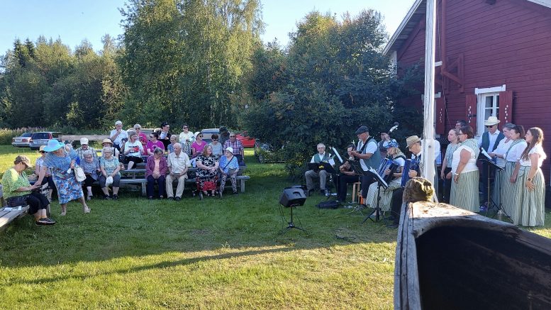 Sekä yleisö että pelimannit viihtyivät paremmin alueen varjoisalla puolella, vaikka jonkin verran kuulijoita uskaltautui myös paahteeseen asenteella "nautittava on kun on kesä". Kuva: Ritva Piri