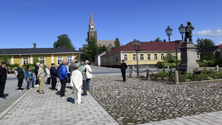 Retkeläiset Raahen Pekkatorilla Pietari Brahen patsaan juurella. Torin laidalla oikealla näkyy Fontellin talo ja vasemmalla Langin kartano. Taustalla Raahen komea graniittikirkko.