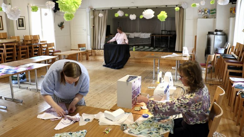 Yli-Olhavan maamiesseurantalon saliin mahtuu levittelemään kankaita tai muita käsityötarvikkeita useampikin osallistuja. Edessä kangasta leikkaamassa Elisa Leppänen ja ompelemassa Annika Ylitalo. Takana Riina Pukema. Kuvat: Tuija Järvelä-Uusitalo