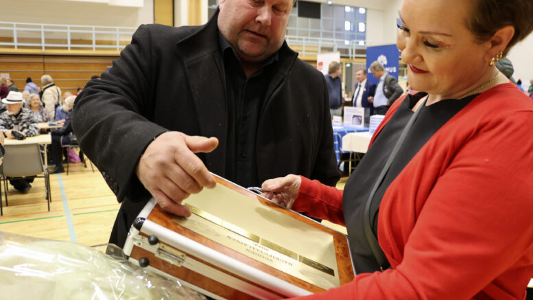 Titta Kivimäki ihastelee saamaansa Vuoden haukiputaalaisen salkkua, jonka laattoihin on kaiverrettu tunnustuksen saaneiden nimiä kautta aikojen. Yrittäjien Seppo Pekkala kertoi, että jaettavan palkinnon nykymuotoonsa on ideoinut Leena Niemelä.