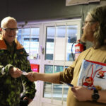 Ville Tenhunen ojentaa Einari Jämsälle seurakunnan "heijastavan tervehdyksen", ristin muotoisen heijastimen Seon huoltamon ovella.