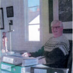 Rolf Stolt työhuoneessaan Kellon Kiviniemessä. Pöydällä on kolme mapillista Kellon historian aineistoa.