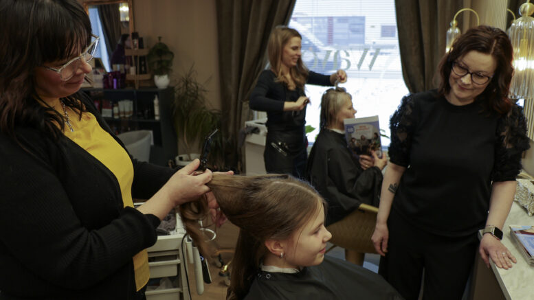Pipsa Kreku tuli leikkauttamaan pitkien hiustensa latvat ja päätyi myös yllätyksekseen malliksi Miia Rannan (vas.) loihtimille muodikkaille laineille. Yrittäjä Kirsi Hanhela korostaa jutussa myös eri alojen paikallisten palvelujen käytön merkitystä, jotta ne säilyvät omalla kylällä. Kuvat: Auli Haapala