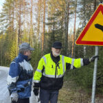 Mutkasta varoittavaa liikennemerkkiä pystyttämässä Veikko Lepikkö ja Jouni Hentilä.