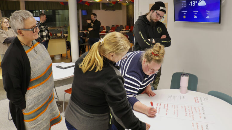 Kuulemistilaisuuteen osallistuneet kirjoittivat ajatuksiaan mahdollisista muutoksista fläppipapereille. Kuvassa kirjoittava Anna Aspegren ja Valtteri Aspegren ovat huolissaan perhepäivähoidon kohtalosta. Pöydän ääressä myös Johanna Kiuttu ja kunnanjohtaja Marjukka Manninen. Kuvat: Tuija Järvelä-Uusitalo