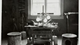 Tunnelmakuva Luostarinmäen käsityöläismuseosta, valokuvaaja tuntematon. Suutarin silmien valonlähteenä ilta-aurinko, pöydän molemmilla puolin suutarin valtaistuimet eli suutarin rummut. Kuva: Turun museokeskus