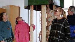 Maailman arvokkain kello -taideteos on valmistumassa. Vapaaehtoisen kellonrakennustiimin Eeva Jämsä ja Anna-Maija Virtanen (vas.) sekä taiteilijapari Tellervo Kalleinen ja Oliver Kochta-Kalleinen tarkastelemassa kellon rakenteita Oravan koululla. Kuvat: Auli Haapala