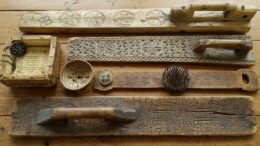 Ylinnä olevista kaulauslaudoista löytyy tyylitellyt päivänkehrät sekä tursaansydän. Hannunvaakunat ovat kantikkaassa juustomuotissa. Pyöreä poronjuustomuotti sisältää runsaasti symboleja: aurinkoristi kera muiden ristien, läpileikattuja kolmikantoja sekä Oinaan merkit. Piikikäs pellavahäkilä on täynnä hakaristejä. Alinna oleva vanha kaulauslauta on lukuisine taika- ja puumerkkeineen mystisin. Kuva: Eino Mikkonen