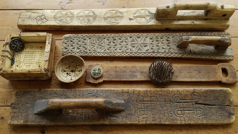 Ylinnä olevista kaulauslaudoista löytyy tyylitellyt päivänkehrät sekä tursaansydän. Hannunvaakunat ovat kantikkaassa juustomuotissa. Pyöreä poronjuustomuotti sisältää runsaasti symboleja: aurinkoristi kera muiden ristien, läpileikattuja kolmikantoja sekä Oinaan merkit. Piikikäs pellavahäkilä on täynnä hakaristejä. Alinna oleva vanha kaulauslauta on lukuisine taika- ja puumerkkeineen mystisin. Kuva: Eino Mikkonen