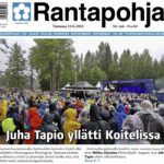Kuvasta näkyy, miten sateisessa säässä Koitelissa juhlittiin vuonna 2025. Yleisö pakkautui seuraamaan Juha Tapion esitystä. Hän yllätti kaikki esittämällä Mikko Alatalon kappaleen Kiiminkijoki.